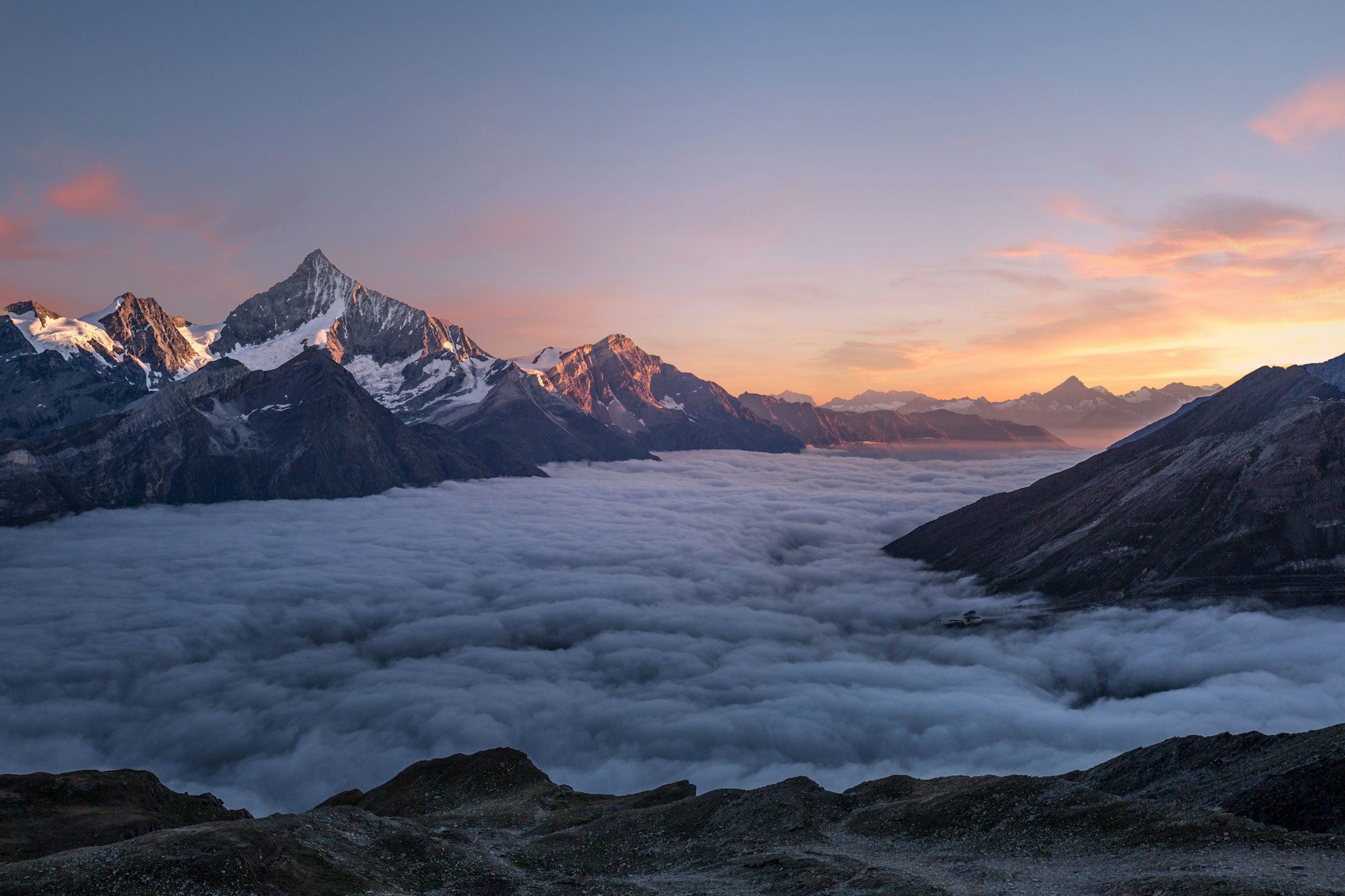 A mountain summit rising clear above a sea of clouds at dawn - clarity above the fog.