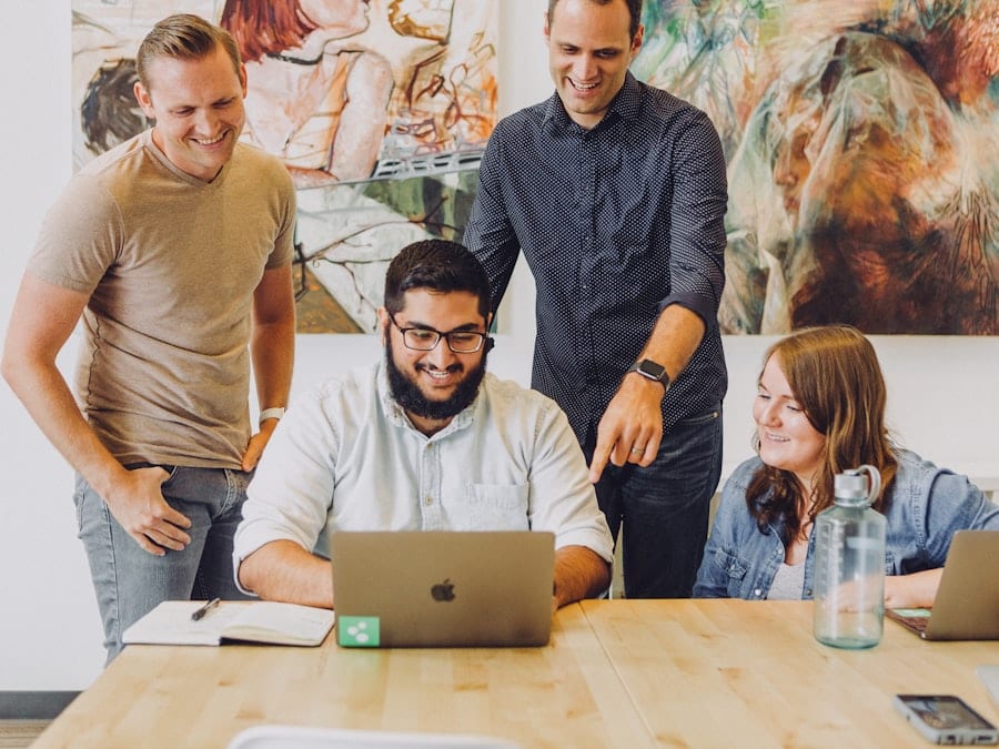 Four colleagues looking at a laptop together at a table.