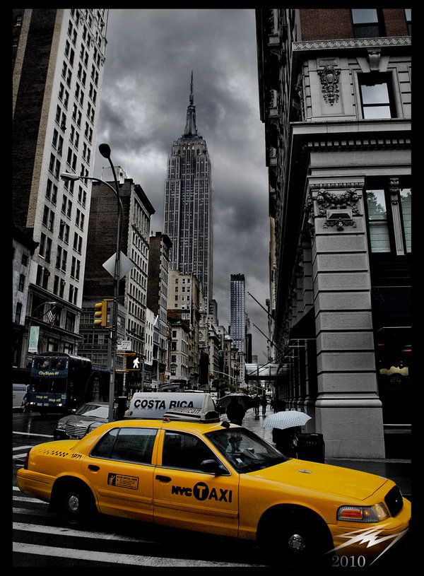 A yellow taxi on a New York City street below the Empire State Building.